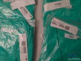 two bags of green surgical gowns sitting on top of each other