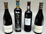 quatre bouteilles de vin sont alignées sur une surface blanche