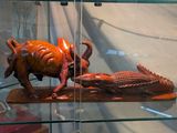 une sculpture en bois représentant un taureau et un crocodile, exposée dans une vitrine