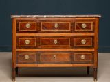 an antique chest of drawers with marble top and brass handles