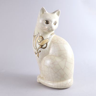 un chat blanc avec un collier doré, assis sur une surface blanche