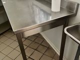 une table en acier inoxydable sur laquelle se trouve une poubelle