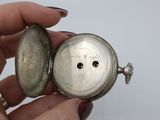 a person holding a silver pocket watch in their hand
