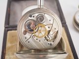 a silver pocket watch inside of a box on a table