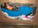 a cardboard box filled with clothes and a blue bag