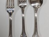 four forks and spoons are lined up on a white surface
