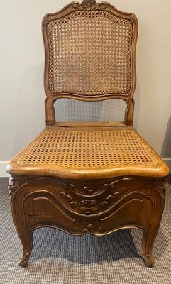 a wooden chair with a wicker seat in a room