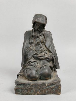 une vieille statue représentant un homme assis sur un bloc de pierre