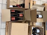 Plusieurs caisses de vin sont empilées les unes sur les autres dans une pièce
