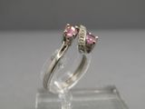 un gros plan d'une bague sertie d'un diamant rose posée sur une surface transparente