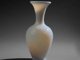 a white vase sitting on a table with a black background