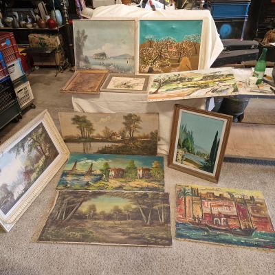 beaucoup de tableaux posés par terre dans une pièce