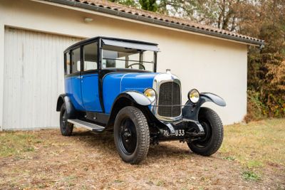 une vieille voiture bleue garée devant un garage