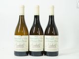 trois bouteilles de vin posées sur une table blanche