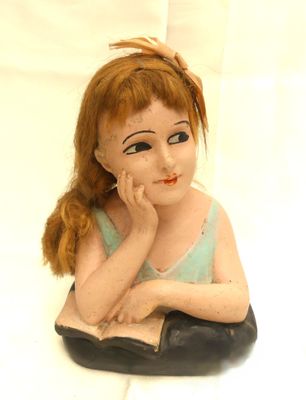 a figurine of a little girl sitting on a white surface