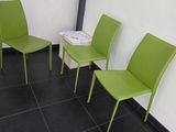Trois chaises vertes sont alignées contre un mur blanc dans une salle d'attente