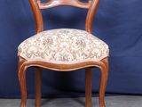 une image d'une chaise en bois dont l'assise est recouverte d'un rembourrage floral