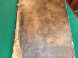 un vieux livre posé sur une table verte, à côté d'une pile de livres