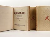trois livres sont ouverts sur une surface blanche ornée d'un motif rouge