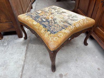 un petit tabouret recouvert d'une tapisserie