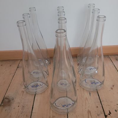 four empty glass vases sitting on a wooden floor