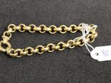 a close up of a gold chain bracelet with a tag on it