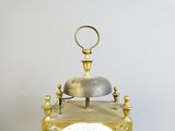 une horloge en or surmontée d'une cloche