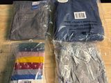 quatre paires de pantalons pour homme dans des sacs en plastique, posées sur une table en bois