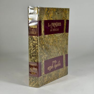 un vieux livre posé sur une table blanche à côté d'un mur blanc