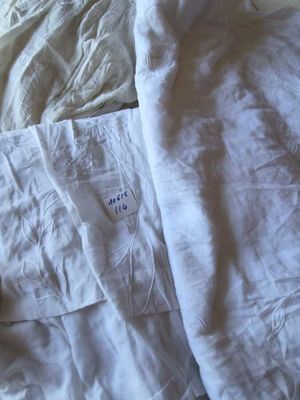 une couverture blanche posée sur un lit, sur laquelle est accrochée une étiquette