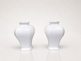 two white vases sitting on a white surface