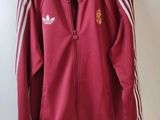 a red adidas track jacket hanging on a hanger