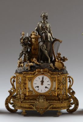 a clock with a statue on top of it next to a vase