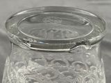 a glass jar with a lid that has a flower design on it