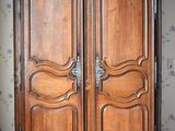 a wooden armoire in a room with a wallpapered wall