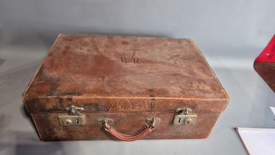 a brown suitcase sitting on a glass table next to a red box