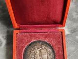 an old silver medal in a red box on a marble surface