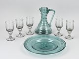 un pichet en verre et six verres à vin sur la table