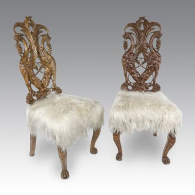 a pair of carved chairs with sheepskin upholstered seats