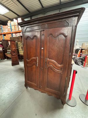 une armoire ancienne dans un entrepôt, avec de nombreux meubles en arrière-plan