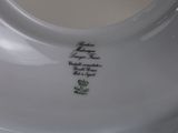 a white porcelain bowl with a gold handle on a table