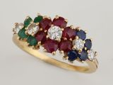a close up of a diamond, ruby, emerald, and sapphire cluster ring