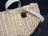 a wicker bag with a metal handle on a black surface