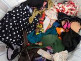 a basket full of clothes and a purse on a bed