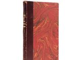 an old book with a red cover sitting on top of a white surface