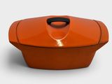 an orange casserole dish with a black handle on a white background