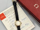 une montre posée sur une feuille de papier, à côté d'une boîte rouge