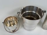 a silver bucket and a silver cup on a white table