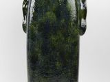 a green vase that is sitting on a white surface
