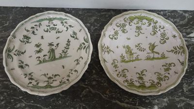 two plates with green and white designs on them sitting on a table